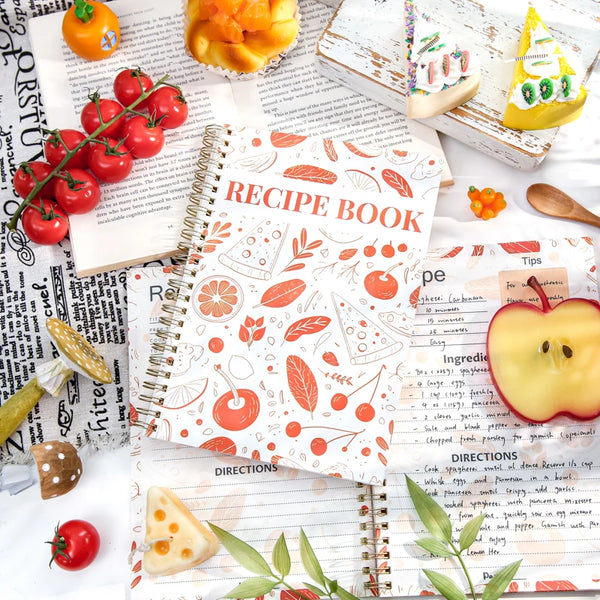 A spiral-bound recipe book filled with handwritten recipes, ingredients, and tips, surrounded by fresh produce.