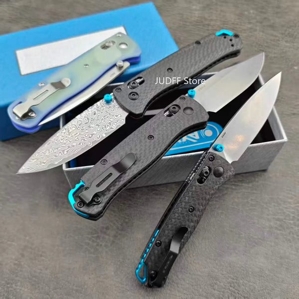 A black folding pocket knife with a silver blade and blue accents is shown inside its box.