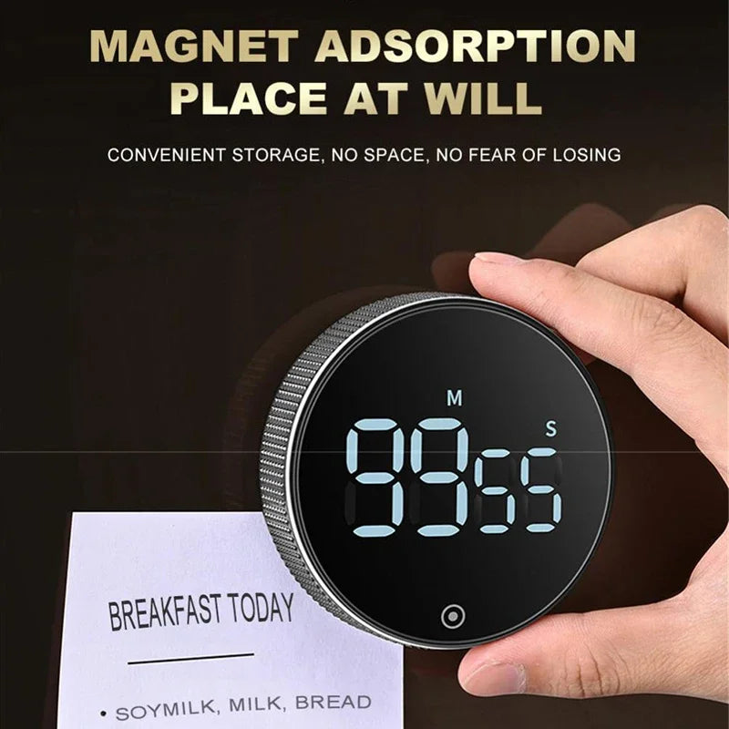A hand holds a magnetic kitchen timer with a digital display showing 99.55, next to a note listing breakfast items.
