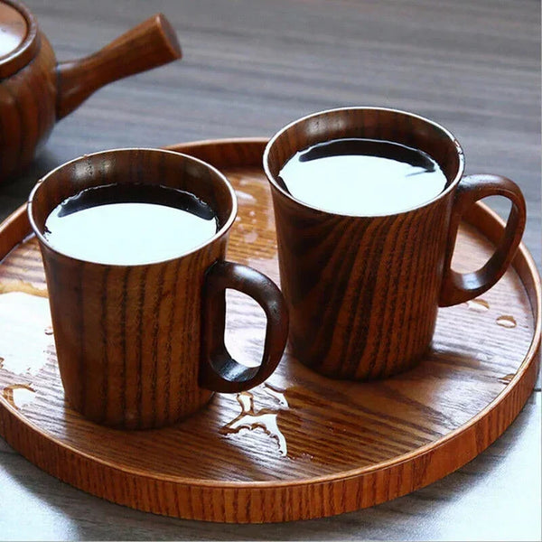 Two wooden drinking cups filled with white liquid are displayed on a wooden plate.