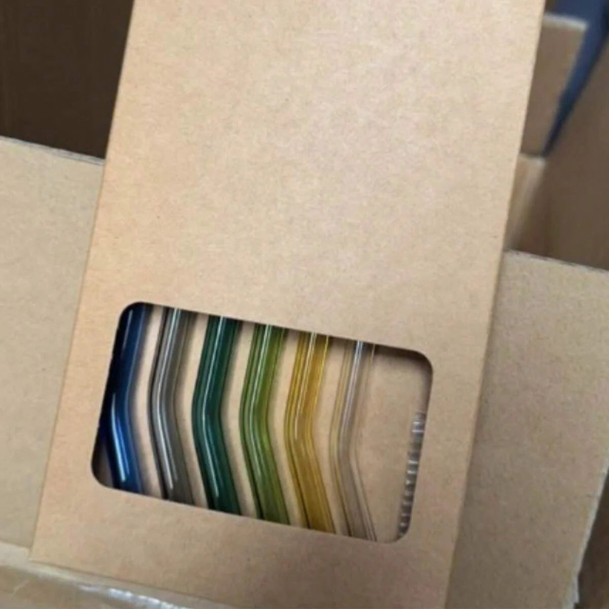 A set of reusable glass smoothie straws in various colors, including blue, green, and yellow, packaged in a cardboard box.