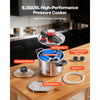 Stainless steel pressure cooker with a steaming rack and tempered glass lid on a wooden table.