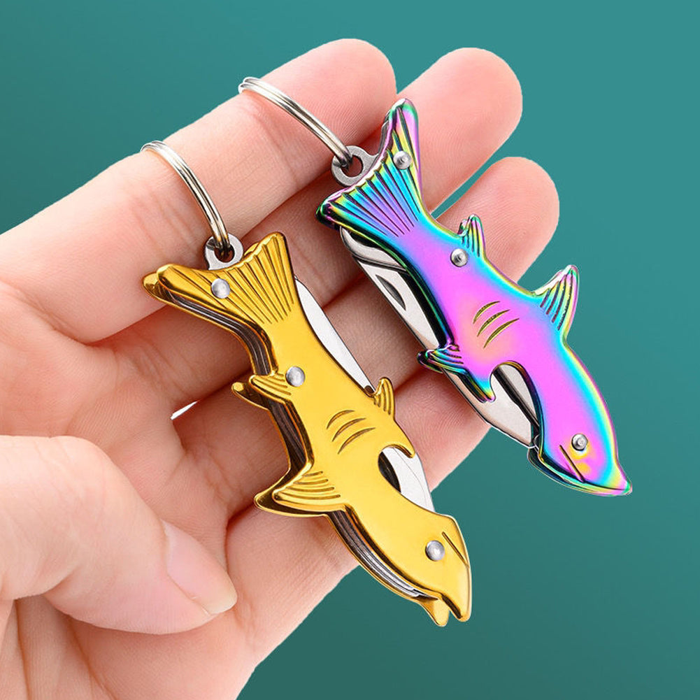A hand holds two colorful stainless steel keychain tools shaped like fish.