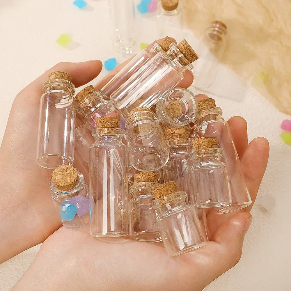A hand holds a set of small glass bottles with corks, used for decorative messages or wishing.