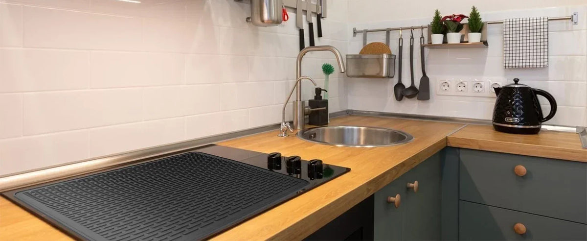 A silicone stove and cooktop protector mat is placed on a wooden countertop in a kitchen setting.