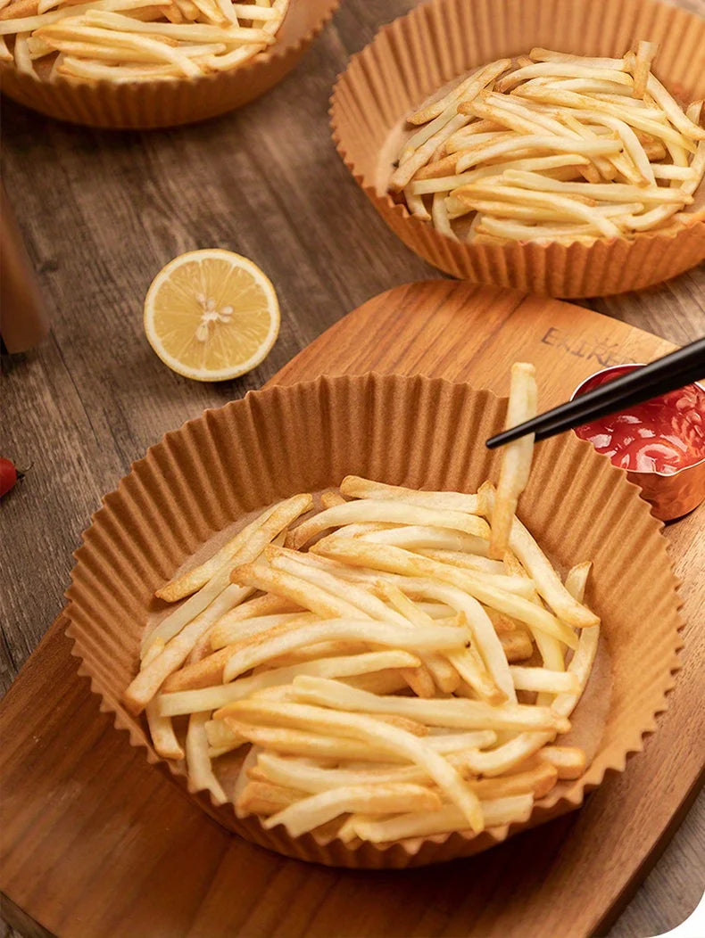Gros plan de frites dorées servies dans des emballages en papier sur une planche en bois.