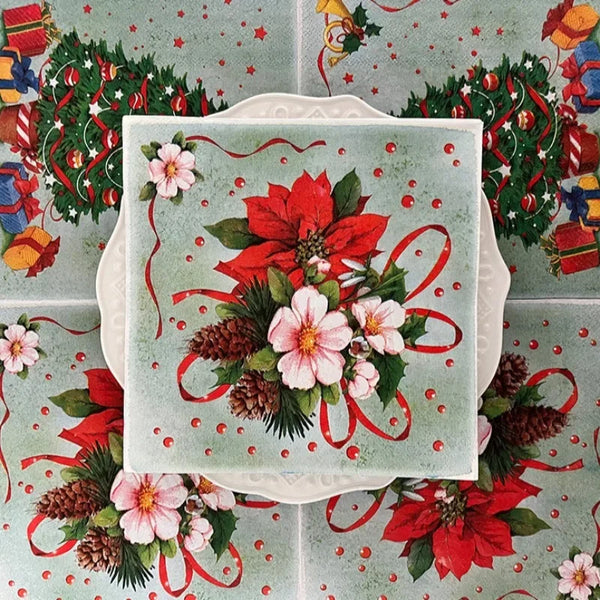 Quadratisches Serviettenmuster mit rosa und roten Blumen sowie Tannenzapfen auf grünem Hintergrund.