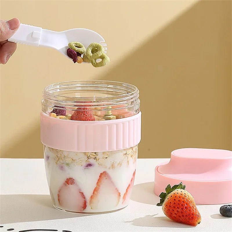 A hand is using a white silicone spatula to scoop green food items from a clear glass jar of yogurt or pudding.