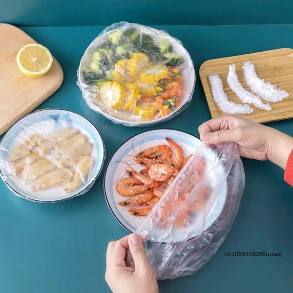 Hands are holding a clear reusable food storage bag filled with cooked seafood and vegetables on a teal surface.
