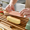 Hands are assembling a silicone mini loaf baking pan set on a wooden cutting board.