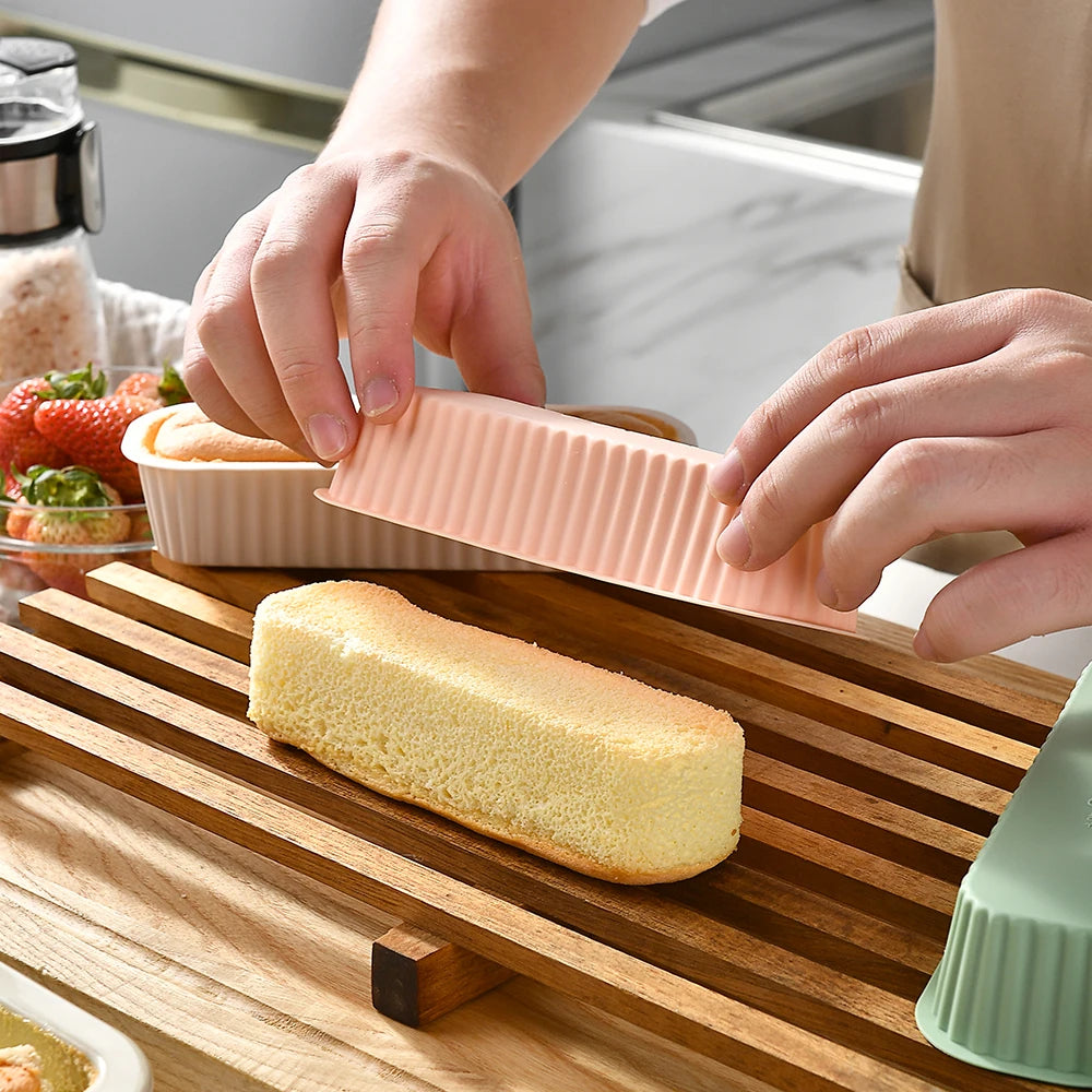 Hands are assembling a silicone mini loaf baking pan set on a wooden cutting board.