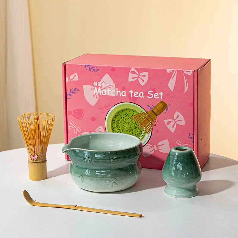 A pink box containing a Japanese matcha tea set with a ceramic bowl and whisk on a white surface.