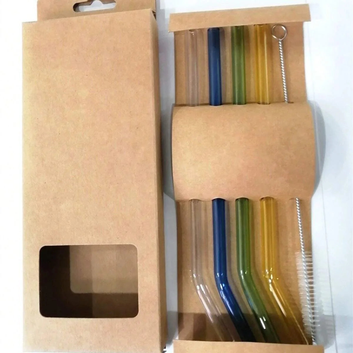 A cardboard box containing reusable glass smoothie straws and a cleaning brush.