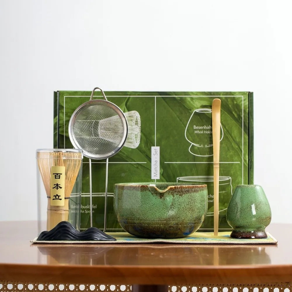 A traditional Japanese matcha tea set featuring a green bowl, whisk, and accessories displayed on a wooden surface.