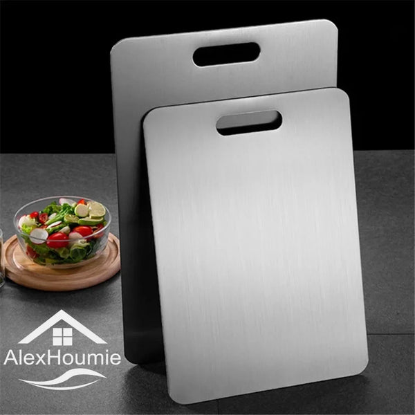 A silver stainless steel cutting board with a handle is shown on a dark surface.