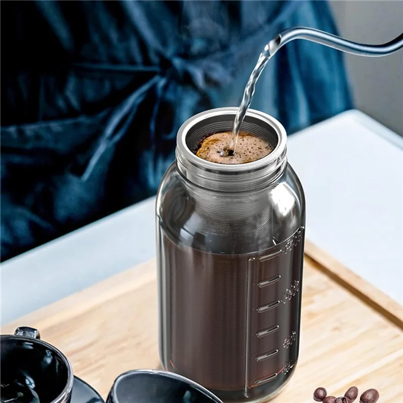 A stream of cold brew coffee is poured into a glass jar, set on a wooden board with other coffee beans.