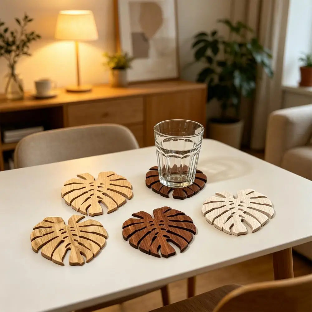 Ein Set aus fünf Holzscheiben mit tropischen Blättern als Untersetzer auf einem weißen Tisch.