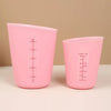A pink silicone measuring cup with volume markings and a digital scale display.