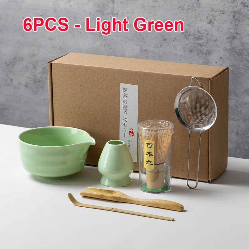 Seis utensilios de té de matcha verde claro, incluyendo cuencos y un batidor, junto a su caja de cartón.