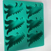A green silicone ice cube tray set molded into dinosaur shapes.