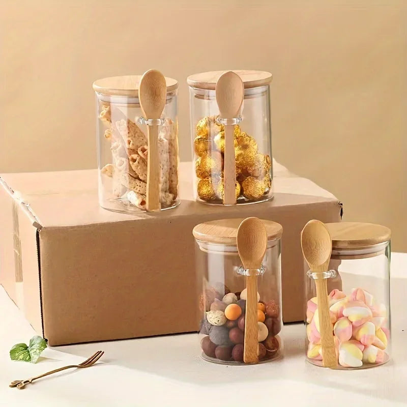 Three glass storage jars with bamboo lids filled with snacks are displayed on a cardboard box.