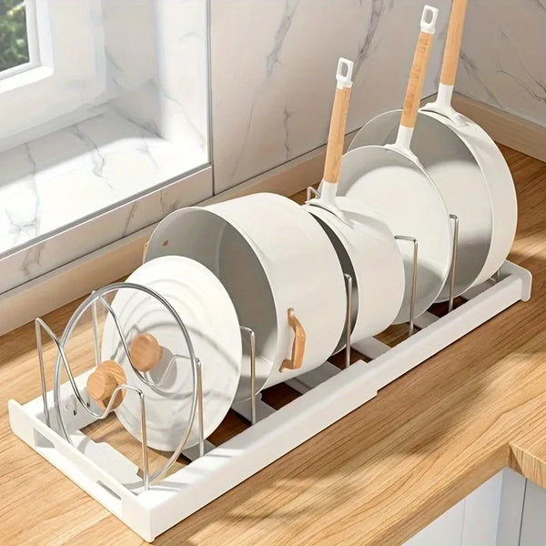 A white expandable kitchen cabinet organizer with adjustable divider racks is displayed on a wooden surface.