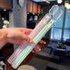 A hand holds a clear plastic chopsticks set with colorful tips, displayed in a modern kitchen setting.