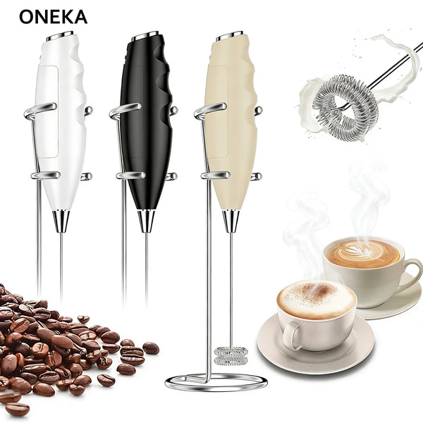 Handlicher Milchaufschäumer in Weiß und Schwarz neben Kaffeebohnen und einer Latte Macchiato.