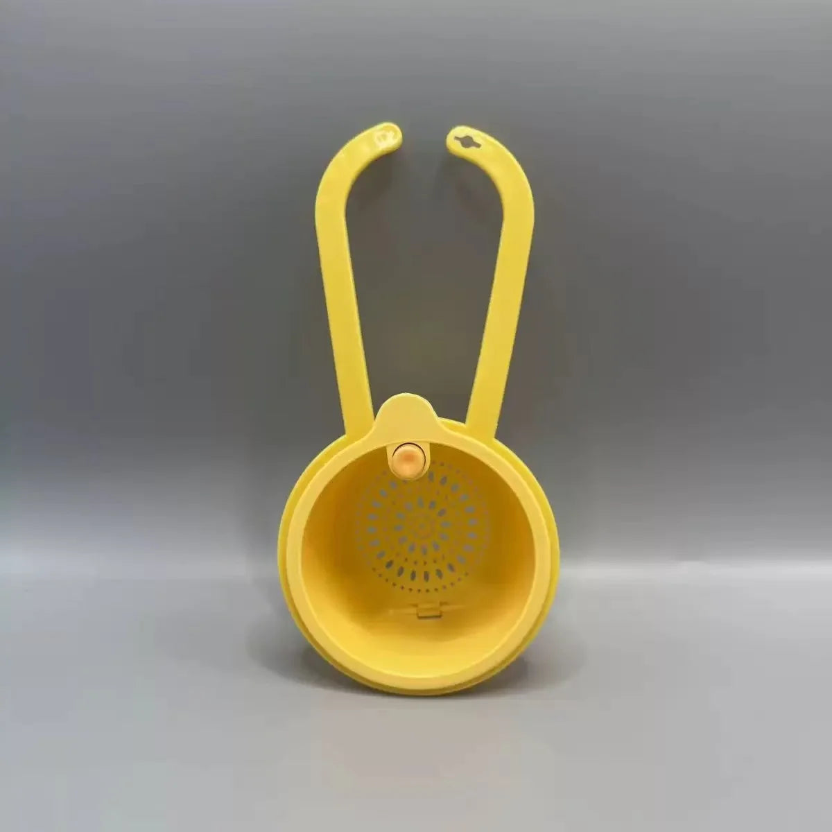 A yellow press-type drain basket with a curved handle is shown against a gray background.