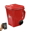 A red novelty trash can with a handle and a black coffee mug next to it.