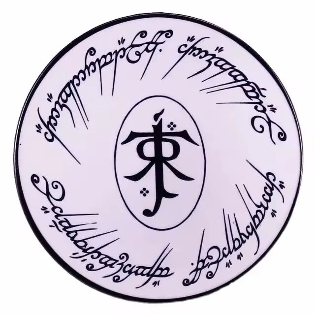 A round enamel pin featuring intricate calligraphy or script on a white background.