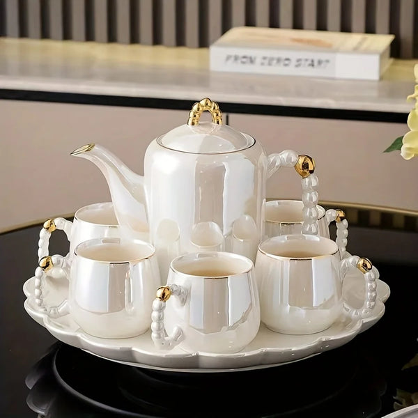 Weiß emailliertes Porzellan-Tee-Set mit Teekanne und drei Tassen mit Goldakzenten.