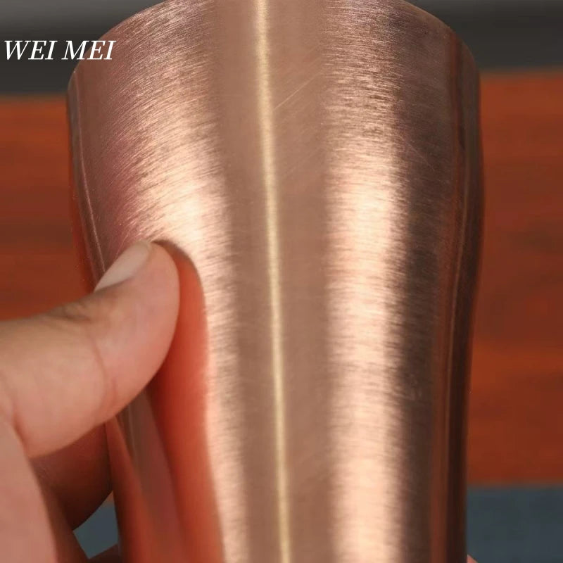 A hand is holding a handcrafted vintage copper coffee mug, showing the smooth texture and warm metallic color.