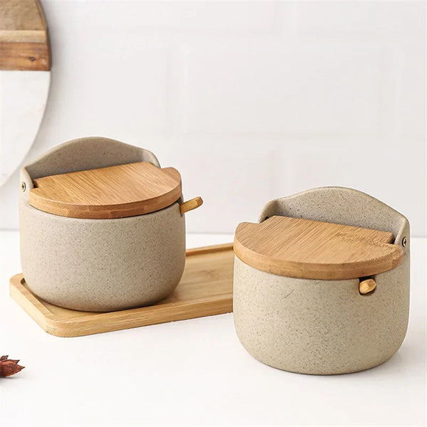 A light beige ceramic seasoning jar with a natural bamboo lid resting on a wooden tray.
