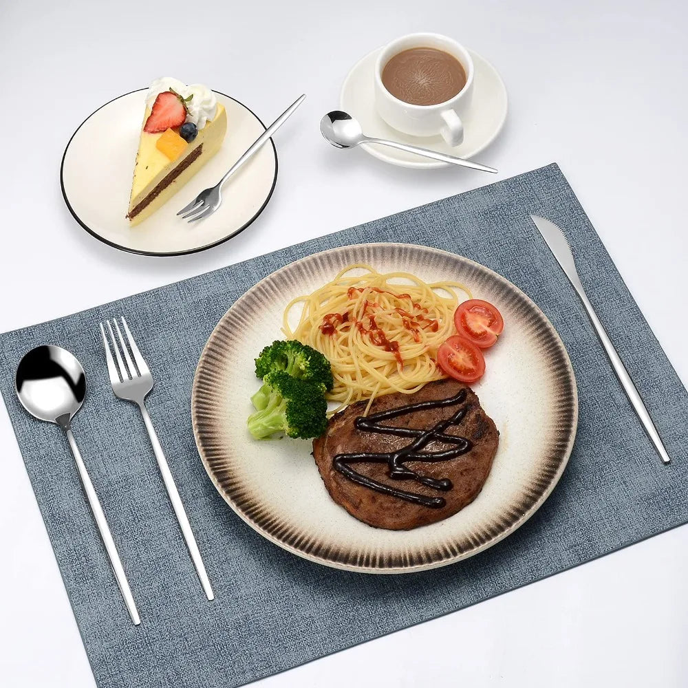 A plate of pasta and a slice of cake served on a dark blue napkin with gold flatware.