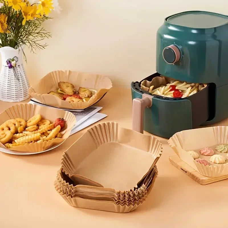 Reusable silicone baking liners in various colors and shapes displayed next to a teal air fryer.