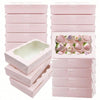 A stack of pink decorative kraft paper candy boxes for gifts, some open to show the interior.