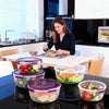 A set of stackable airtight food storage containers in various sizes and colors on a kitchen counter.