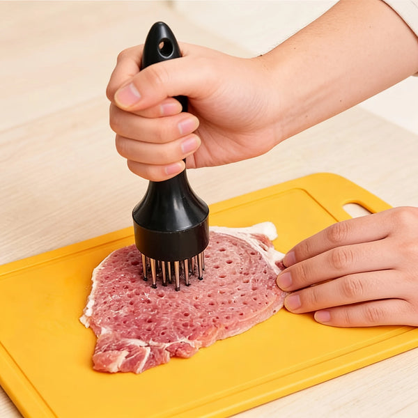 Eine Hand benutzt ein Edelstahl-Fleischzarterwerkzeug, um rotes Fleisch auf einem gelben Schneidebrett zu klopfen.