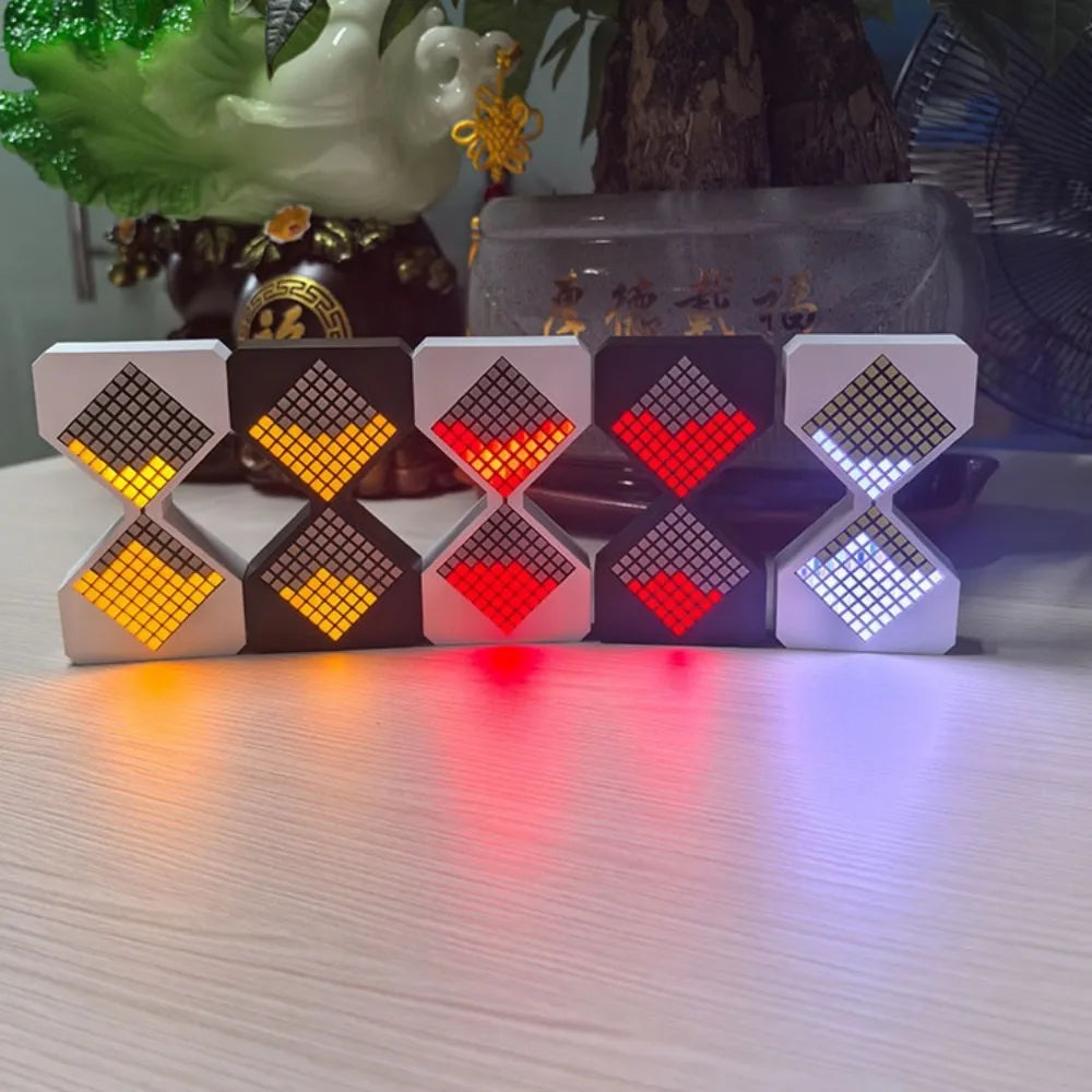A set of black and white LED digital hourglass timers with red and yellow lights resting on a light surface.