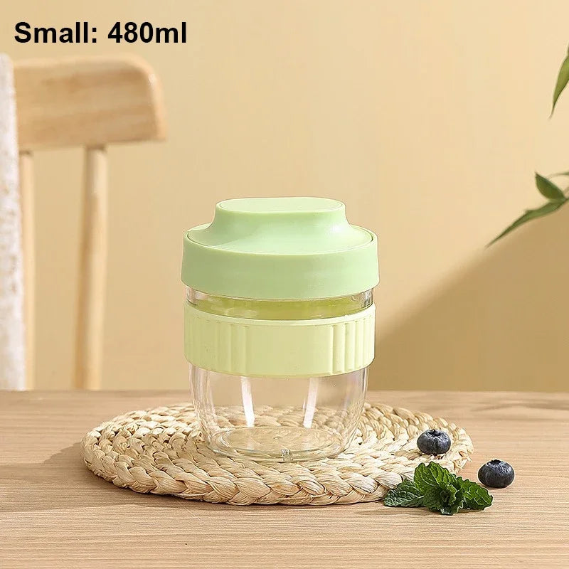 A small light green reusable and leakproof portable food container sitting on a woven mat.