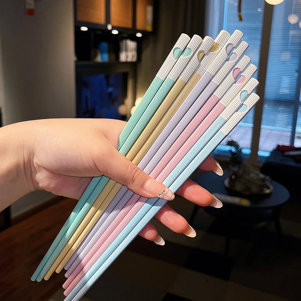 Eine Hand hält ein Set bunter Legierungspickel mit pastellrosa, blau und cremefarbenen Spitzen.