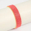 A stack of pink acrylic elastic bracelets with gold accents worn on a wrist.