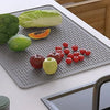 A silicone induction cooker protector mat displaying various fresh vegetables and fruits on a white surface.