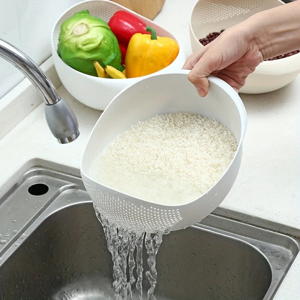Eine Hand gießt weißen Reis durch ein Küchensieb in eine Edelstahlspüle.