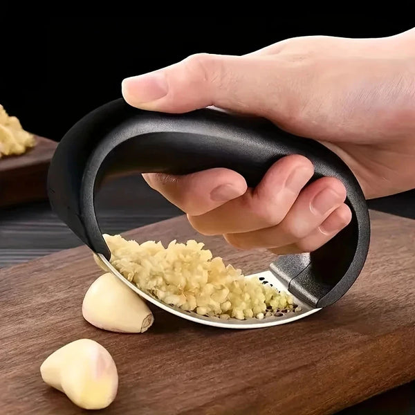 Eine Hand hält eine schwarze Edelstahl-Knoblauchpresse und -Mörser, mit zerdrückter Knoblauch auf der Schale.