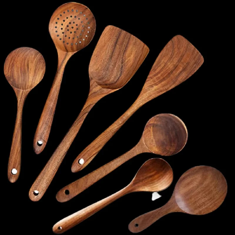 Un ensemble d'ustensiles de cuisine en bois naturel, incluant cuillères et spatules, sur fond noir.
