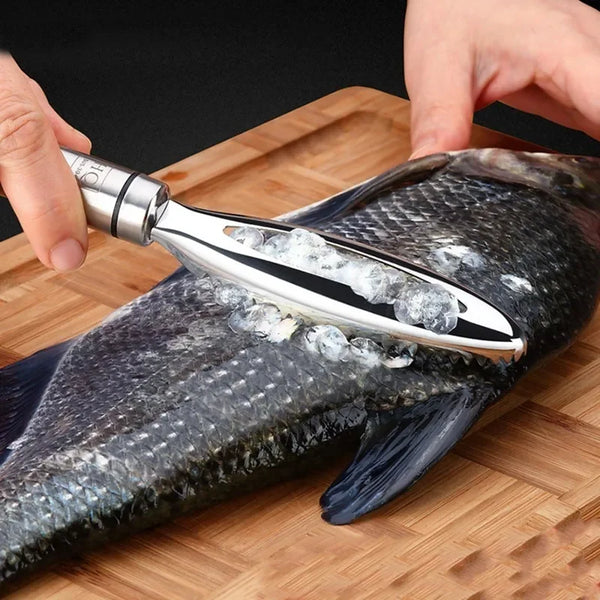 Eine Hand hält einen Edelstahl-Fischmaß-Schaber und eine Pinzette auf einem Holzbrett mit einem Fisch.