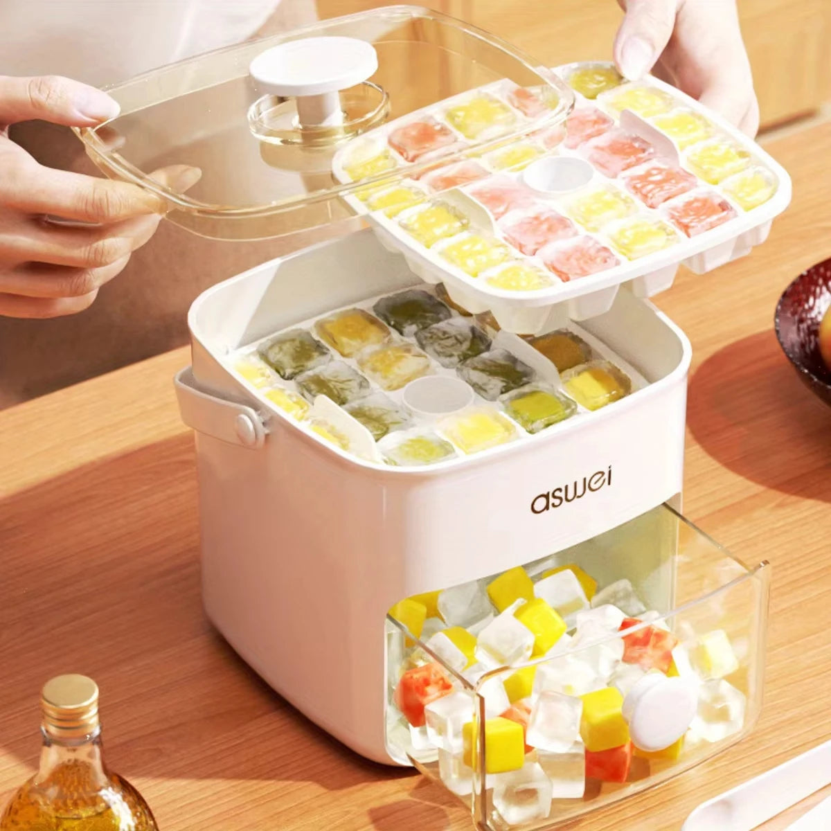 A hand is holding a large capacity double-layer ice cube maker with various colored ice cubes on a wooden surface.