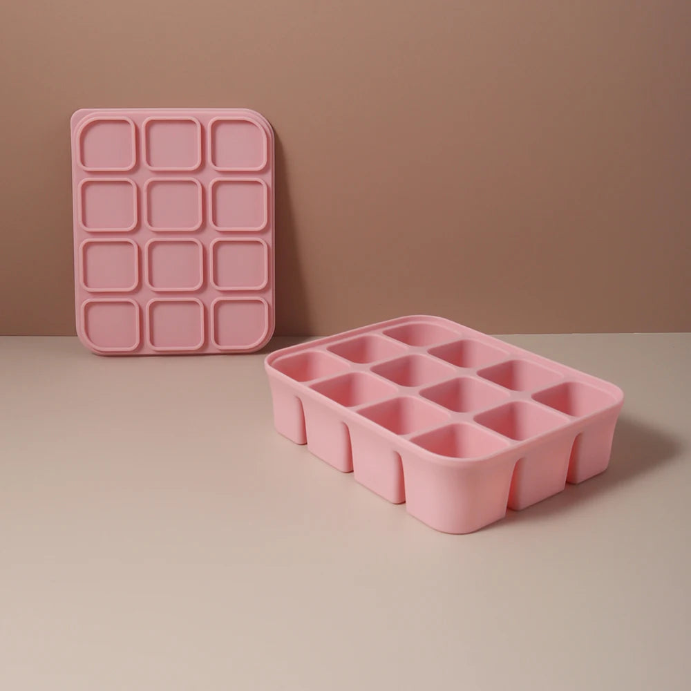 A pink silicone food tray with multiple compartments is shown on a light surface.